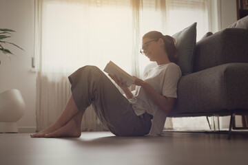 Happy woman sitting on the floor and reading a book