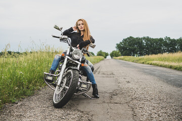 Biker girl posing on a motorcycle. Summer motor bike trip background.