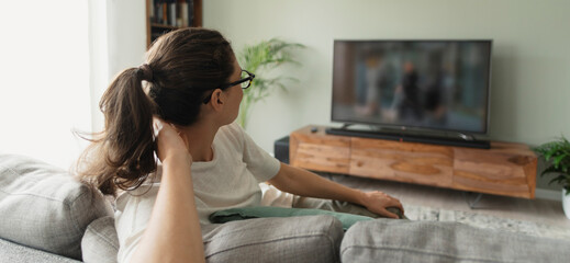 Woman sitting on the sofa and watching TV