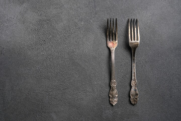 Cutlery forks isolated on a grey marble background. The minimalist monochrome photograph of the dish.