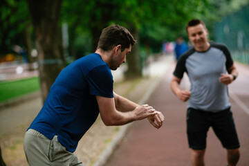 Young men training on a race track. Two young friends running on athletics track	
