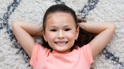 Little Girl Posing Lying On Carpet At Home, Panorama, Above-View