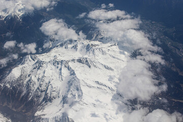 Fototapeta na wymiar Widok z samolotu. Alpejski góry. Śnieg i puchaty chmury.