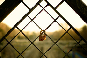 backlight of a closed padlock on a fence in a sunset