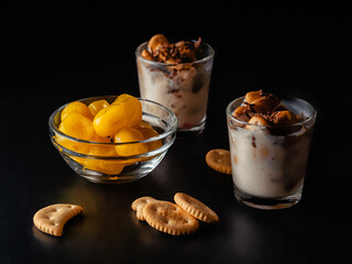 dessert consisting of chocolate biscuit yogurt and dried fruits on a dark background in glass