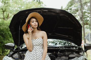 A young Asian tourist is talking on the phone to call her car insurance company to check the condition of her car. Caused by unknown reasons