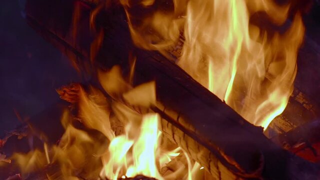 Slow motion - Close-up campfire at the night. Large burning fire in the forest, at the night. Low angle view to the fire with large flames. Burning fire of large logs on an autumn evening.