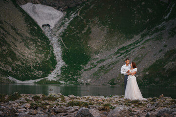Fototapeta na wymiar Portrait of a young beautiful couple. Hug each other against the backdrop of a mountain lake. Copy space
