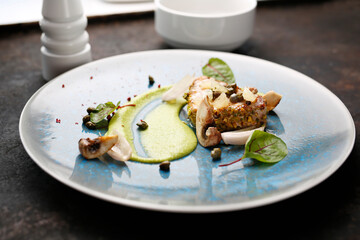 Grilled tuna steak with pistachio nuts, capers and green peas. Tasty dish on a blue plate. Food photography.