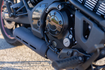 Detalle de motor de motocicleta con reflejo de luz natural en el exterior sobre asfalto