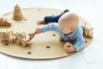 Baby boy playing with wooden toys lying on the Mat. Ecology, education, upbringing concept