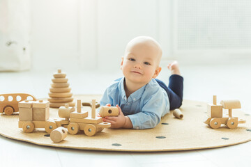 Baby boy playing with wooden toys lying on the Mat. Ecology, education, upbringing concept