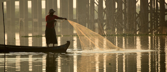 Local fisher man use fish net catch fish in Taungthaman lake near u-bein bridge, Mandalay, Myanmar (Burma)
