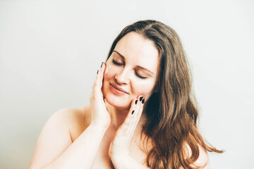 Smiling pleasant woman doing a facial massage.