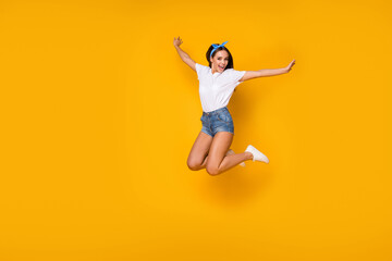 Fototapeta na wymiar Full size photo of dreamy lovely cute excited girl jump raise hands enjoy spring free time weekend holiday wear good look blue headband sneakers isolated over bright color background