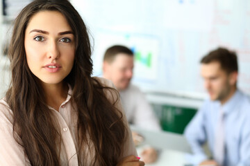 Beautiful young lady looking at camera and keeping mouth slightly open. Two men on blurred background