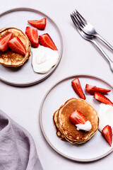 Homemade pancakes with strawberry and whipped cream (chantilly) on grey concrete background. Selective focus