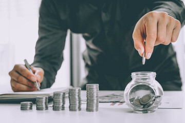 saving money with hand putting coins in jug glass concept financial
