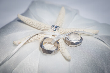 wedding rings on a white pillow with seafish as decoration