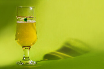 A glass of beer on green background and clover souvenir hanging on the glass