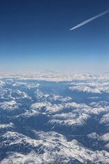 Widok z samolotu na góry Alpejskie. Śnieg na górach gór. Na horyzoncie ślady od innego samolotu.