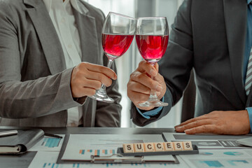 Two businessmen are sipping wine in the office, working to celebrate the success of the company business,success and winning concept.