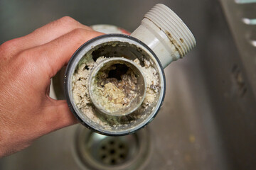 clogged sink pipe,in the hands of a clogged dirty sewer pipe from leftover food