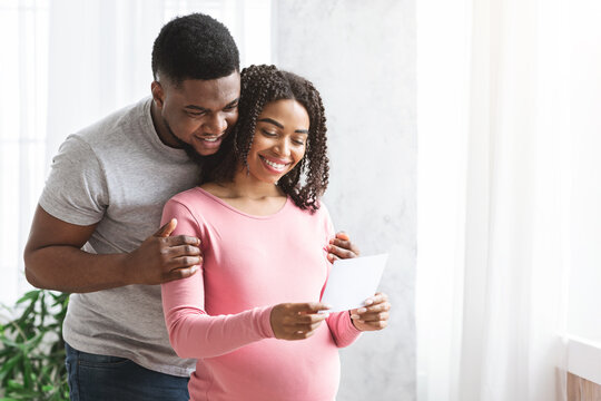 Cheery pregnant woman and her husband looking at image