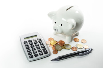 White ceramic piggy bank with coins and a calculator on a light background, economy concept for...