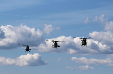 Trzy helikoptery latają nad Gdańskiem. Niebo jest w chmurach.