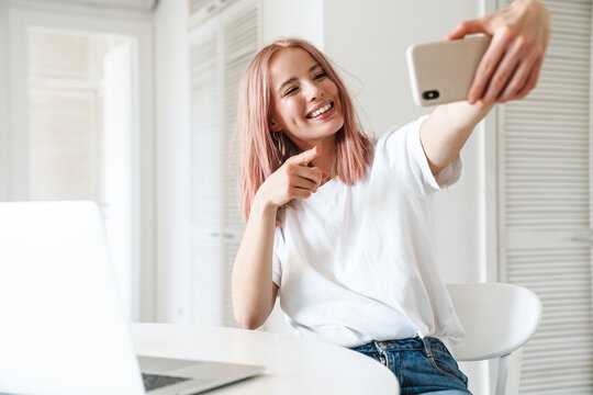 Photo of woman pointing finger and taking selfie on mobile phone