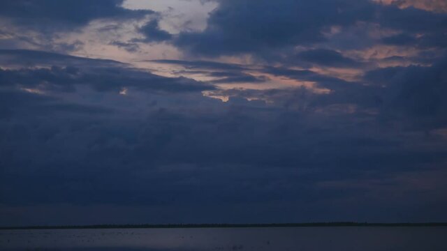 The sky is in zagon with clouds above the pond. Sunset time.