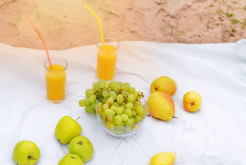 outdoor picnic - fruits and orange juice on a white tablecloth on the beach