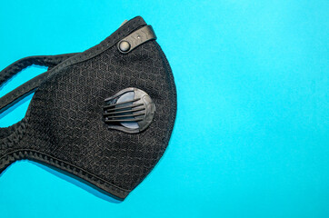 Black activated carbon dust mask with filters on blue background with copy space. Top view. Safety...