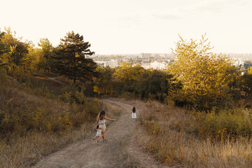 Joyfull young mother spend wonderful holiday time in the forest with her kid. Two blondies, mother and daughter