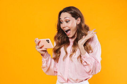 Image of delighted woman expressing surprise and using mobile phone