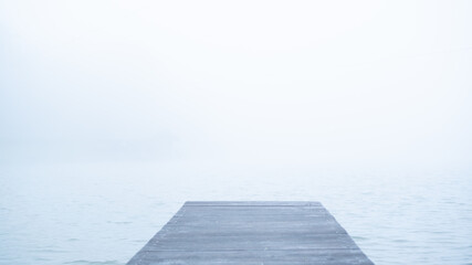 Concept of lonely wooden abandoned dock in fog. Sad and calm mood background. Mist and alone pier. Wallpaper