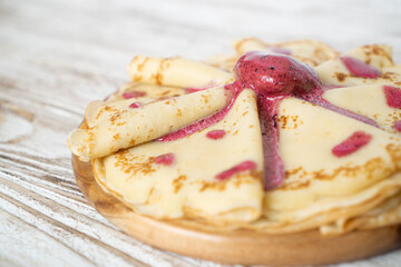 Breakfast with hot pancakes and strawberry ice-cream. Delicate and delicious pancakes on a wooden plate with red jam