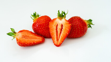 Fresh red strawberries cut into slices with green petals lie on a colored background. Healthy lifestyle