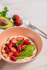 Summer salad with strawberries, avacado and cream cheese on a white wooden background.