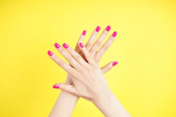 Beautiful hands of a young woman on a yellow background. Beautiful manicure close-up.