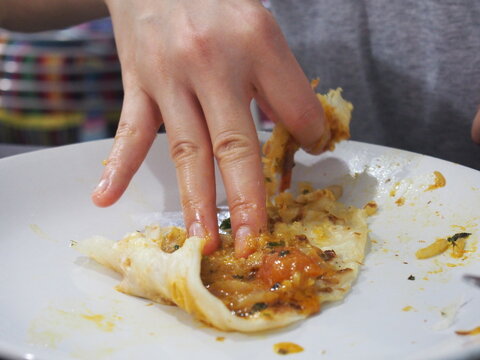 A woman eating a parotta with her hands., Kochi (Cochin), India