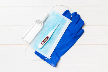 Top view of latex gloves, bottle of alcohol hand sanitizes, medical mask and digital thermometer on...