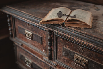 old vintage keys on an old battered book, wooden background.