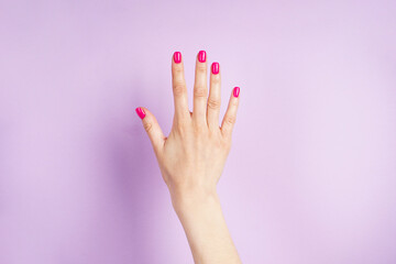 Beautiful hand of a young woman on a purple background. Beautiful manicure.