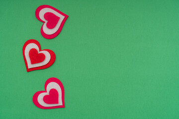 Vertical red hearts on a green background. Copy space.