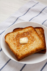 Homemade Buttered Toast on a white plate, low angle view. Copy space.