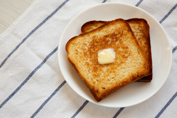 Homemade Buttered Toast on a white plate, high angle view.