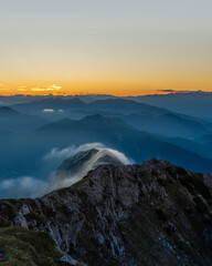 layers of mountains during sunset with a fog cloud