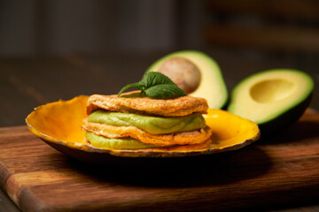 Low Carb Keto Diet Pancakes from almond coconut flour stack on plate with avocado mousse on wooden table background close up view. Selective focus. Ketogenic concept